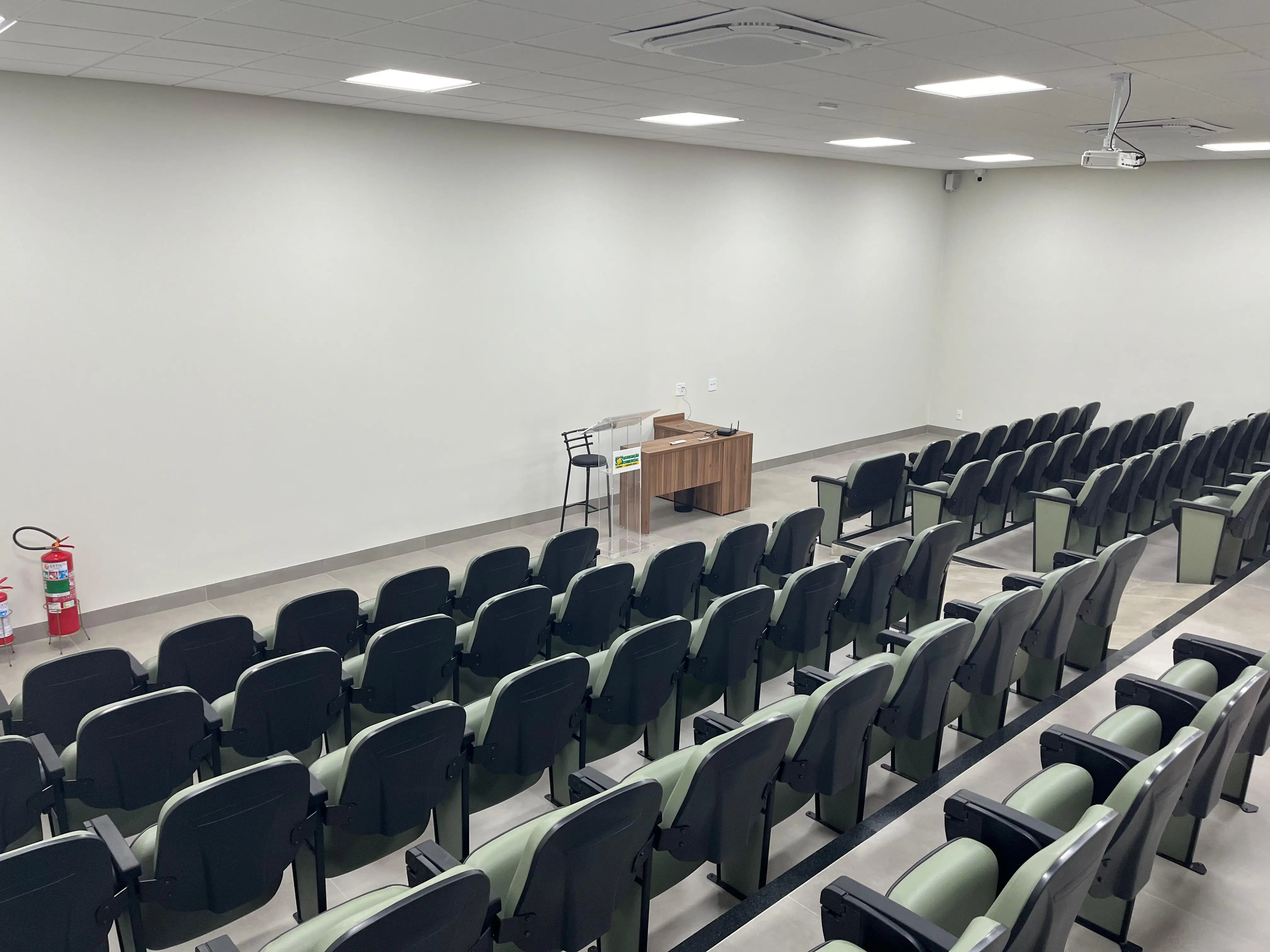 Na foto mostra as cadeiras do auditório na visão onde mostra a mesa do palestrante.