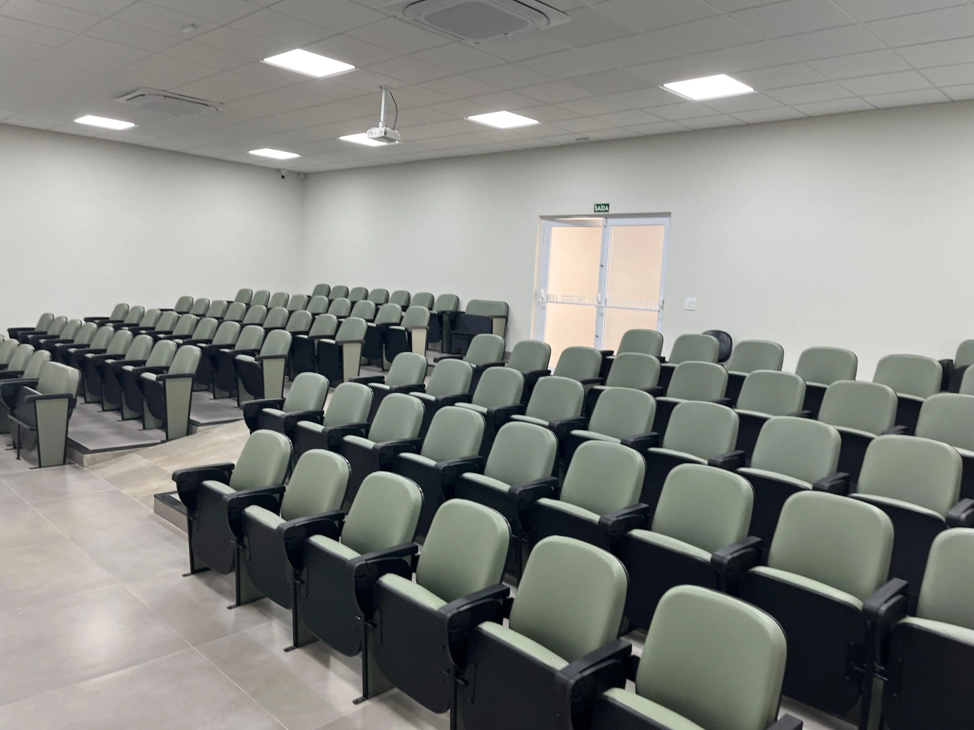 Na foto mostra as cadeiras do auditório na visão de canto direito, onde mostra a saída e entrada do auditório.