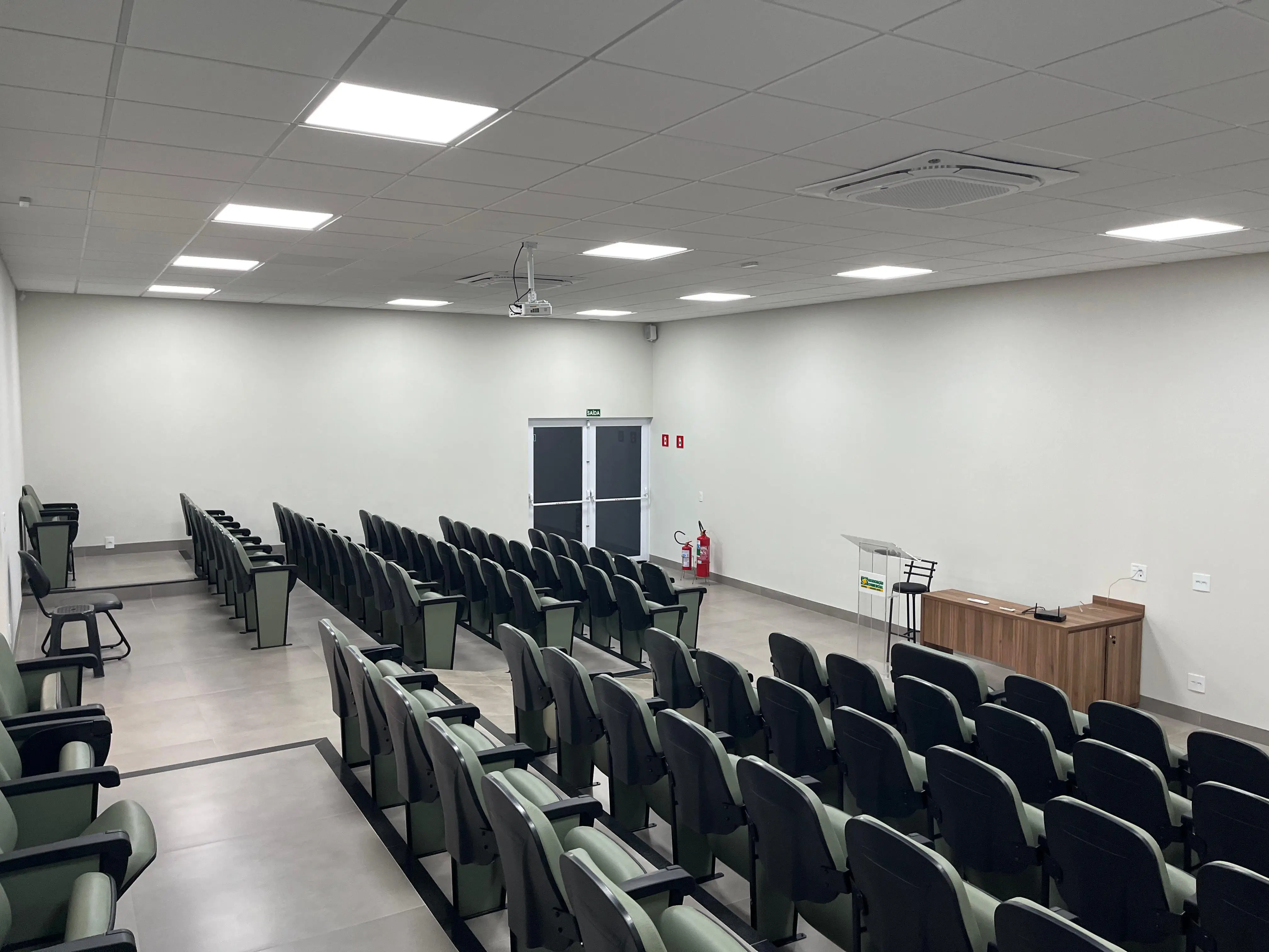 Na foto mostra as cadeiras do auditório na visão onde mostra a mesa do palestrante.